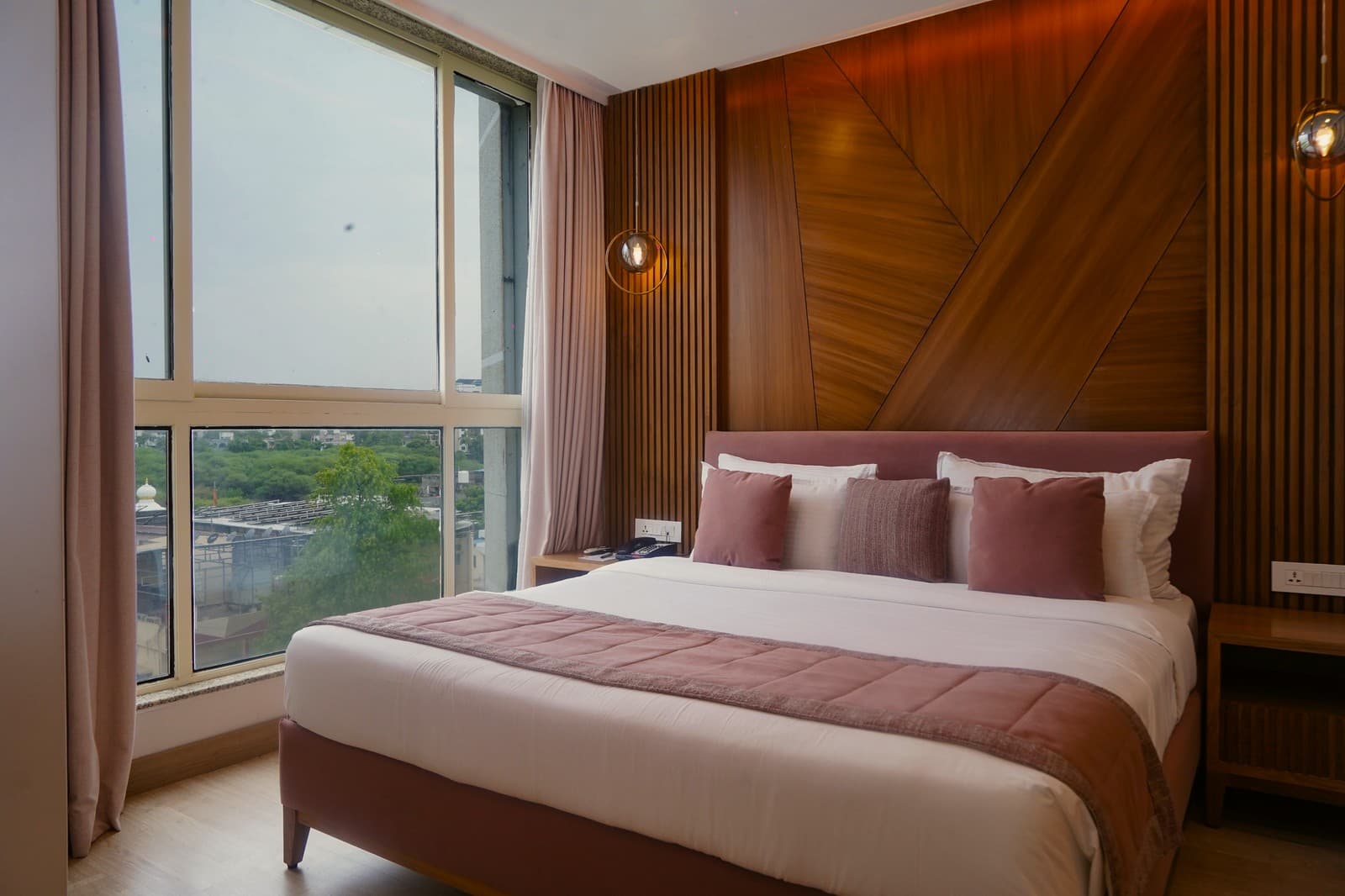 A guest room with a timber-panelled wall and a rose upholstered bed.
