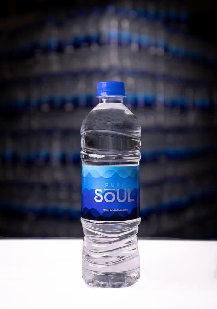 A bottle of Puro Soul mineral-enriched water in front of the bottling line.