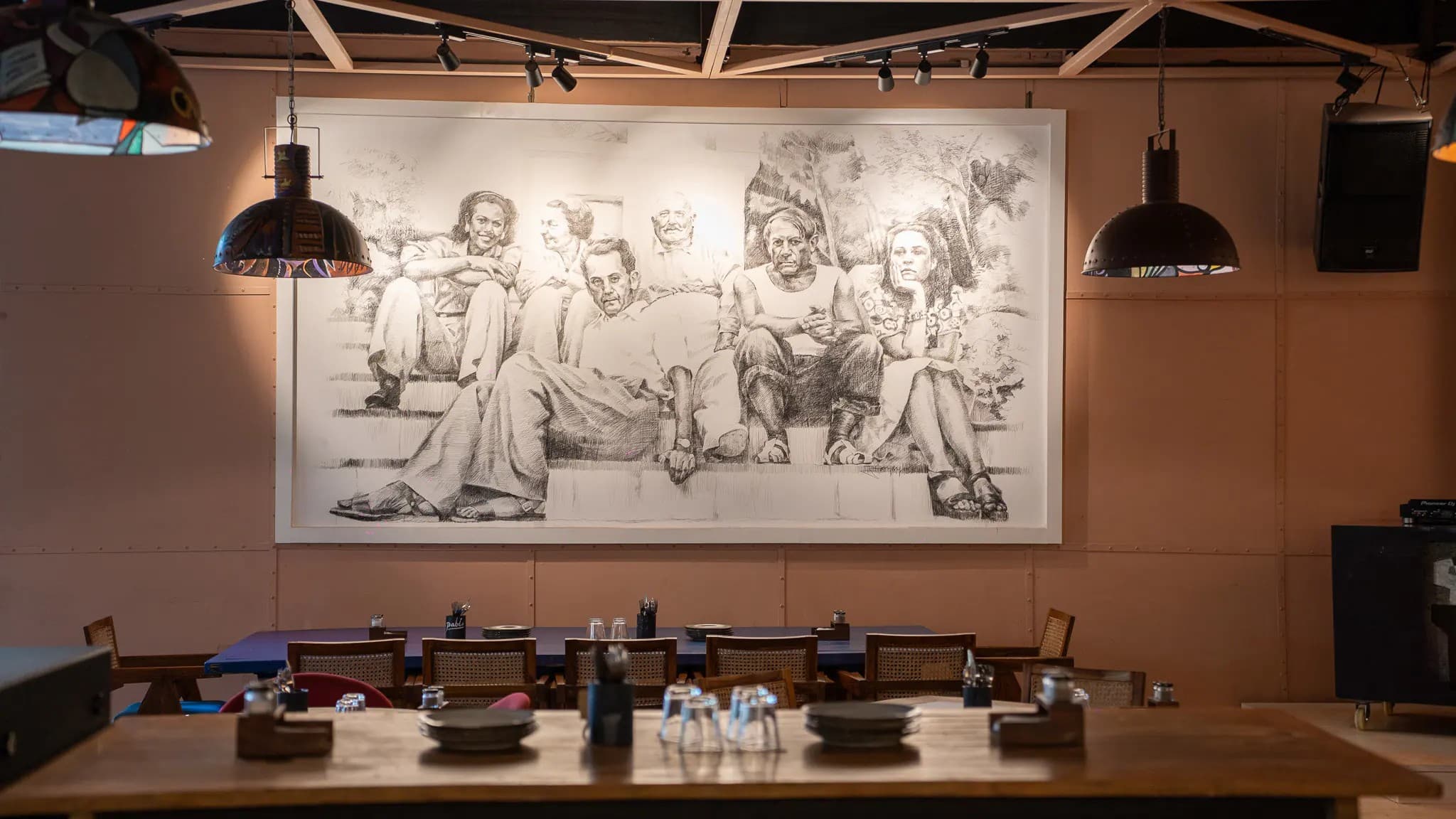 Pablo's dining room beneath a large pencil mural of figures seated on steps.