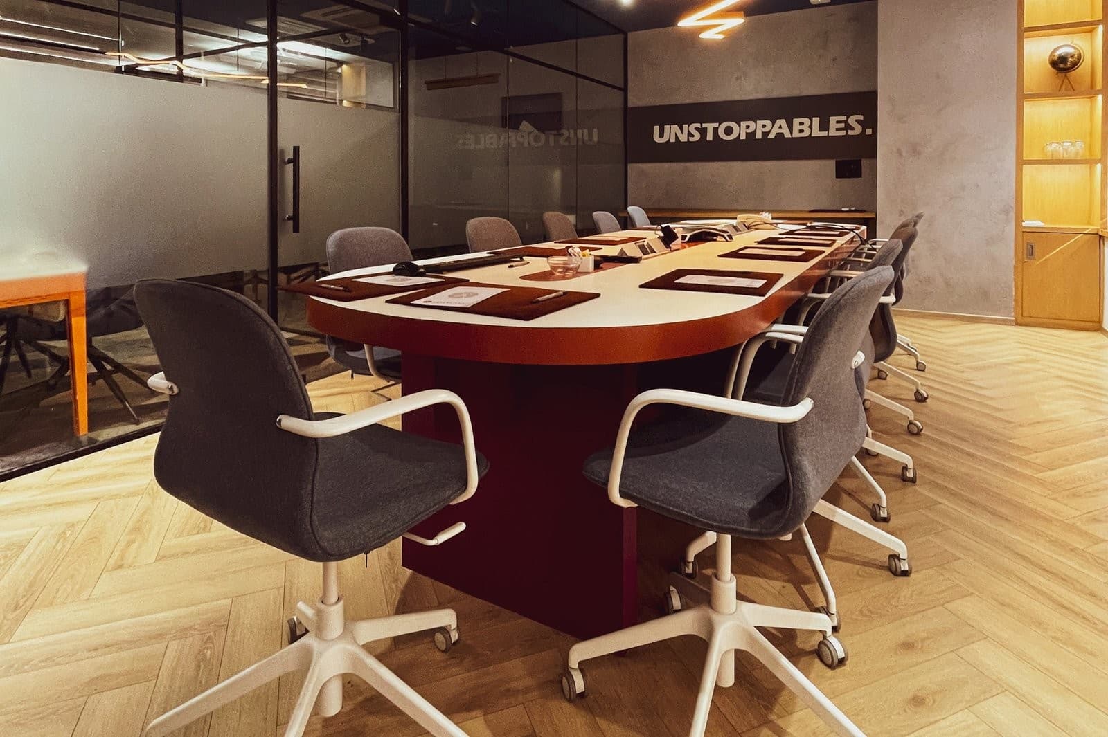 A boardroom with a long table and the word “Unstoppables” on the wall.