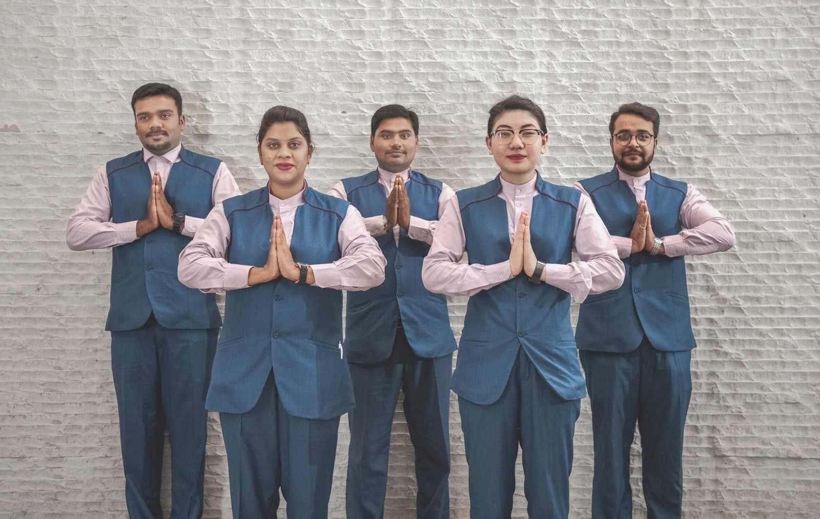 Five members of the Centre Point team in uniform, greeting with a namaste.